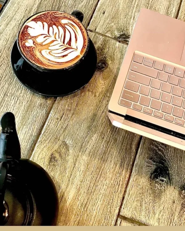 A coffee with leaf art on one of our timber tables